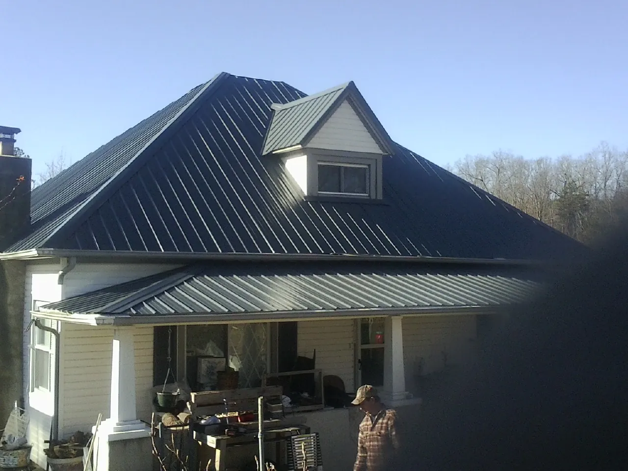 Dark blue standing seam metal roof with a dormer above a front porch in Noxon