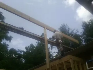 Carpenter setting a ridge beam over a new addition frame — Ice Dam Removal by Roofing Brothers in Noxon