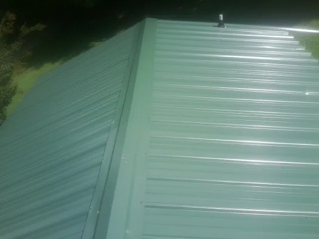 New green metal panels meeting at the ridge of a roof — Flat Roof Repair work by our crew in Noxon