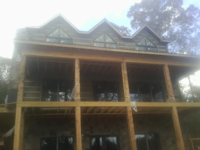 Dormers and porch framing on a large log home under construction — Roof Coating work by our crew in Noxon