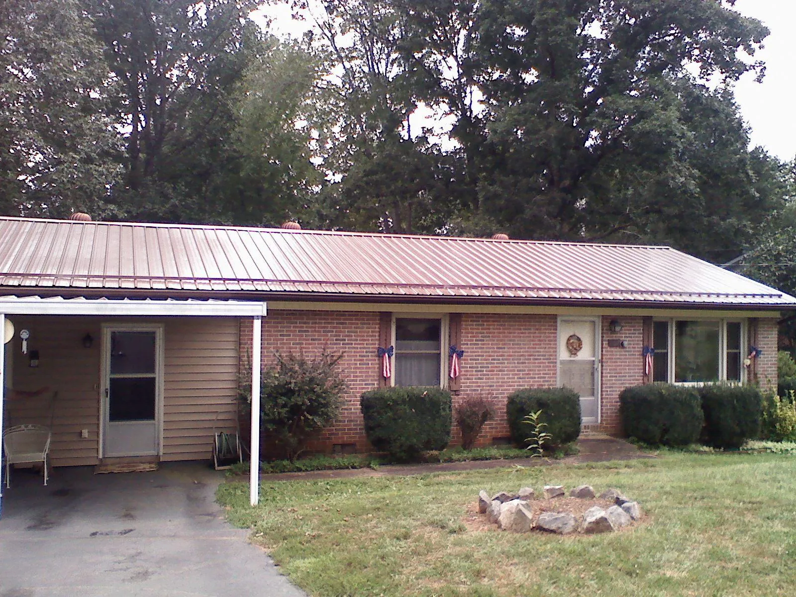 Bronze metal roof and carport on a brick ranch home — Roof Repair work by our crew in Noxon