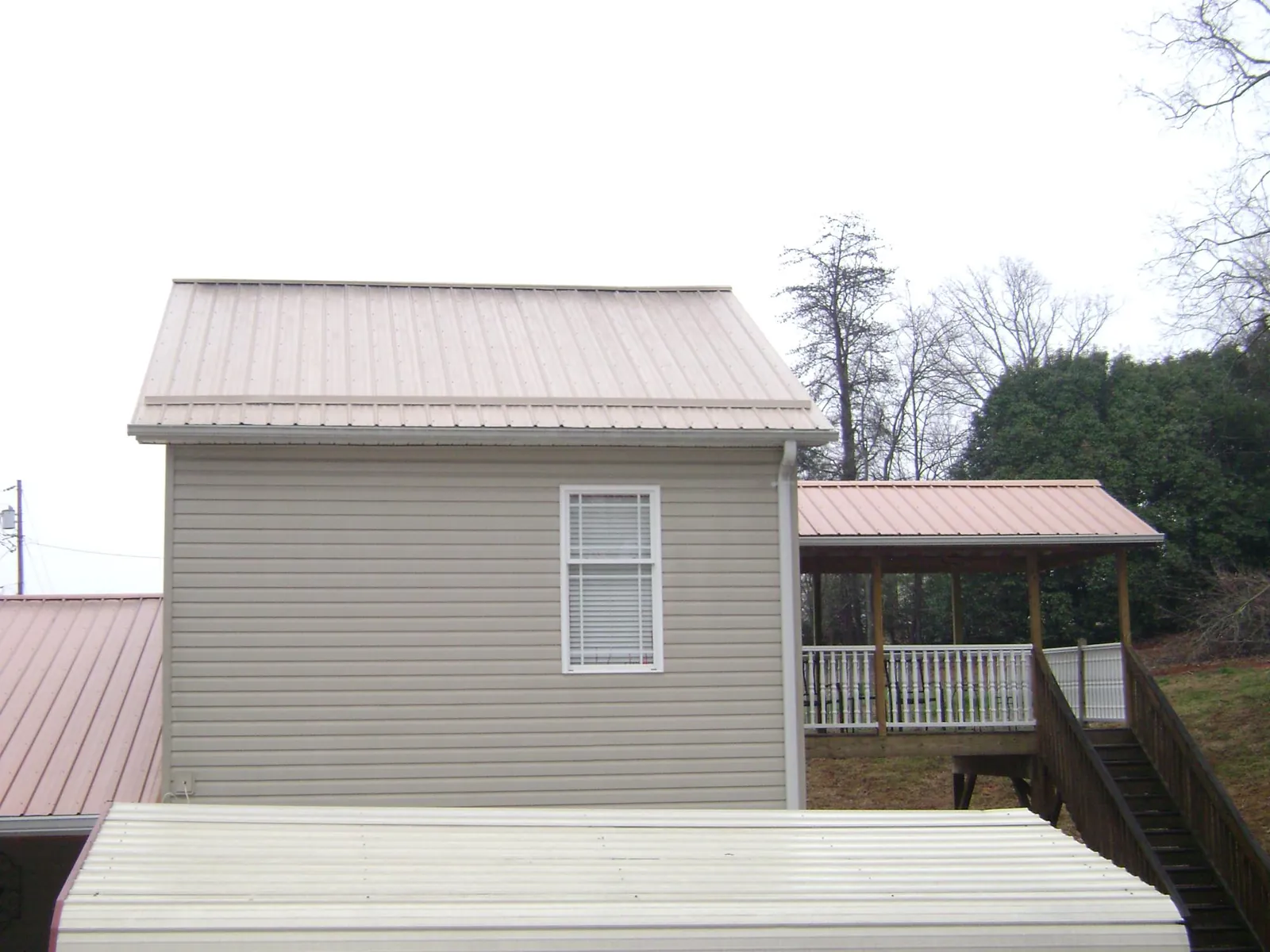 Tan metal roofs on a two story addition and attached porch, from a Roof Replacement job in Noxon