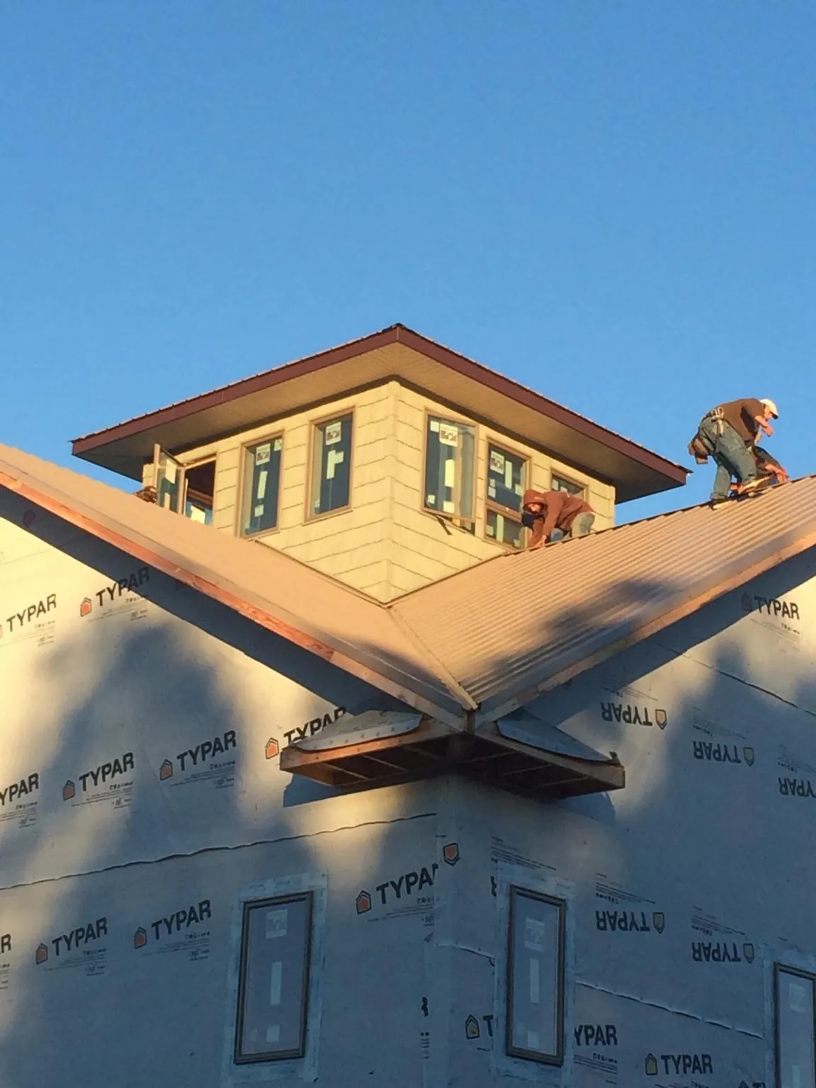 Roofers working around a rooftop cupola on a new metal roof at sunset — Roof Waterproofing in Noxon by Roofing Brothers